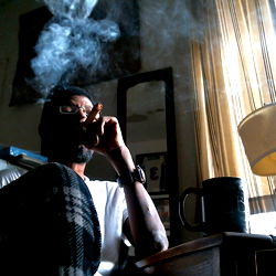 A Man Sitting in a Window with Cigarette and Glasses