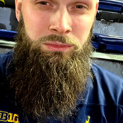 Man with a beard wearing sports gear and a jersey