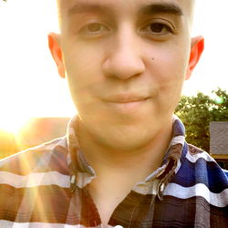 Cool and casual outdoor portrait of a man with short hair, sporting a plaid shirt and blue jeans.