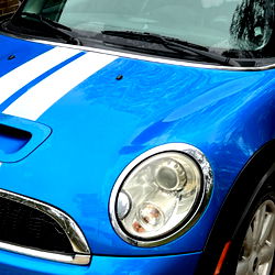 Blue Mini Cooper with Racing Stripes in a Driveway