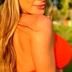 OnlyFans Model Poses in Red Bikini Against Outdoor Background