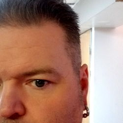 A man with a bald head and a beard, taken from a low angle. Onlyfans model name is B.