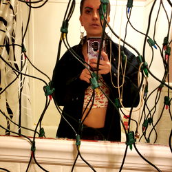 Onlyfans Bobbie in a Christmas-themed room with string lights and a mirror