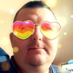 A man in a vibrant photo with a rainbow background and heart-shaped sunglasses