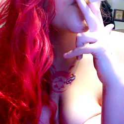 A young adult woman smoking a cigarette while sitting in front of a computer