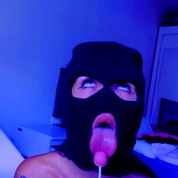 Model in Black Mask Holds Lollipop, Tongue Out
