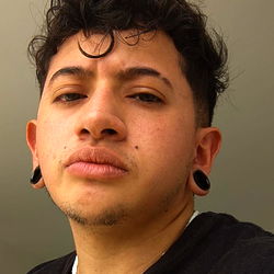 Alejo, a young adult male with a piercing and tattoos from Colombia.