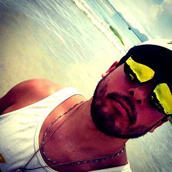 Man in sunglasses with hat and tank top on beach