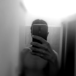 A Shirtless Man Taking a Selfie in the Mirror