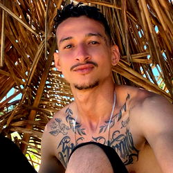 Allan Queiroz, a Tattooed Individual in a Straw Shack