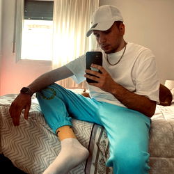 A person seated on a bed, checking phone