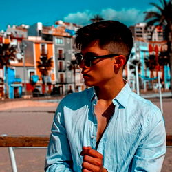 Alberto on a beach, with palm trees in the background and sunglasses.