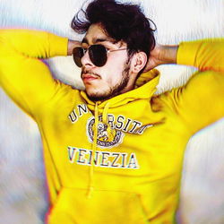 Alejandro Gaona, a young man from Venezuela, poses confidently in a yellow hoodie.