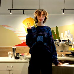 Ollie, a cool young man in a trendy café, peacefully signaling his hipster vibe