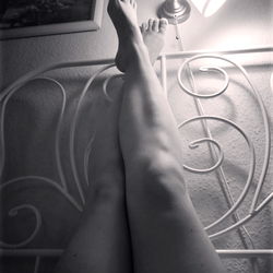 Sexy Female Legs on a Bed with Wrought Iron Headboard