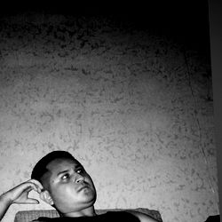 Adonis in a black sleeveless shirt leaning against wall