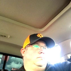 Man in orange and black baseball cap, taking selfie in car
