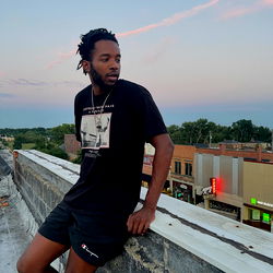 Young man posing on rooftop at sunset with tattoo sleeve