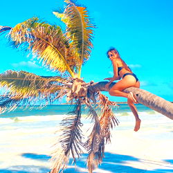Poshspicy model poses in a tropical setting near the ocean