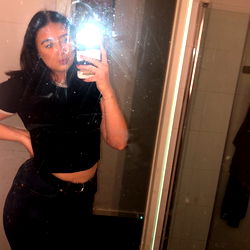 A candid moment captured in a mirror image. OnlyFans model Amanda, 25 years old, strikes a pose in her black crop top.