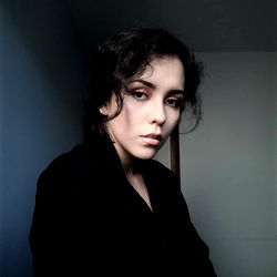 Alx, a young woman with short hair and a contemplative gaze.