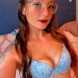 ForbiddenFruit, a model on OnlyFans, strikes an enticing pose in this image with her pink crop top and blue bra.