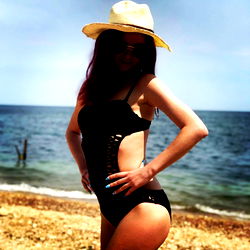 Aesha_Rich, a striking model in a swimsuit on the beach