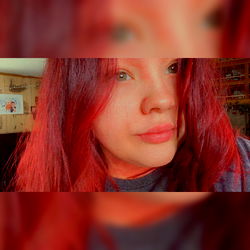 A young adult female with vibrant red hair and a casual pose