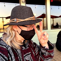 Man with long hair in mask signaling peace symbol