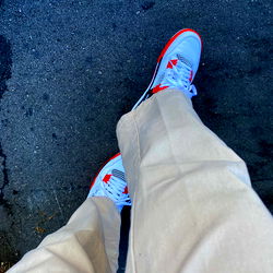 Casually Dressed Person Walking on Sidewalk with Red Sneakers