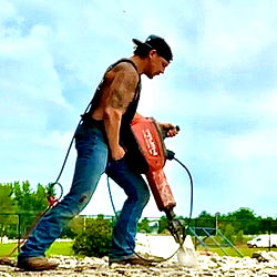 Muscular Man Using a Chainsaw on a Construction Site