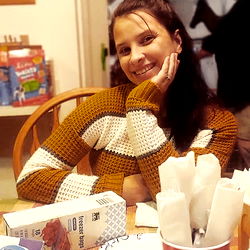 Smiling Woman in Multi-colored Sweater at Dinner Table