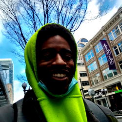 A Smiling Person in a Hoodie and Scarf in a Busy Street