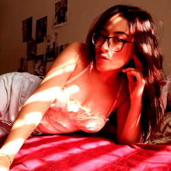 Young Woman Laying on Bed with Red Hair and Glasses