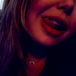 SJ, a social media influencer, poses for OnlyFans with a seductive lip piercing and tongue out.