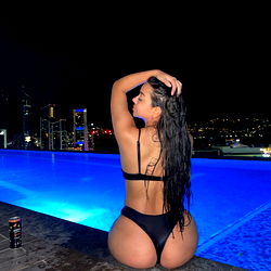 Adalez, a stunning OnlyFans model poses for a captivating swimsuit photo with a poolside backdrop at night