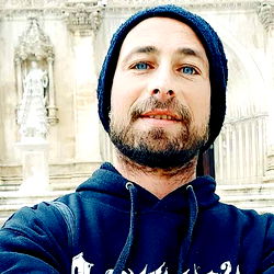 Man in Beanie and Hoodie posing with a historic building