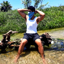 Cleverly posed for the camera, Alain Mendoza sits atop a rustic wooden bench by the water.