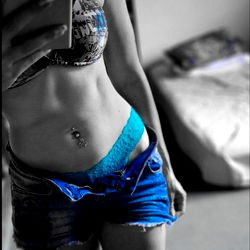 Alyssa, a stunning OnlyFans model, showcasing her physique in a black and white photo. She is captured from behind, with her toned muscles highlighted under the light.