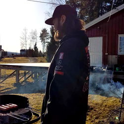A person standing by a grill on a sunny day