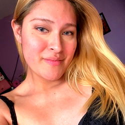 Blonde woman in bra and underwear with a neutral expression. She has long hair and is looking slightly away from the camera.