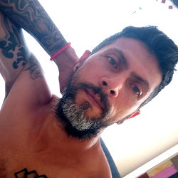 Andrés Granada: Tattooed Man in Shirtless Selfie with Intense Expression